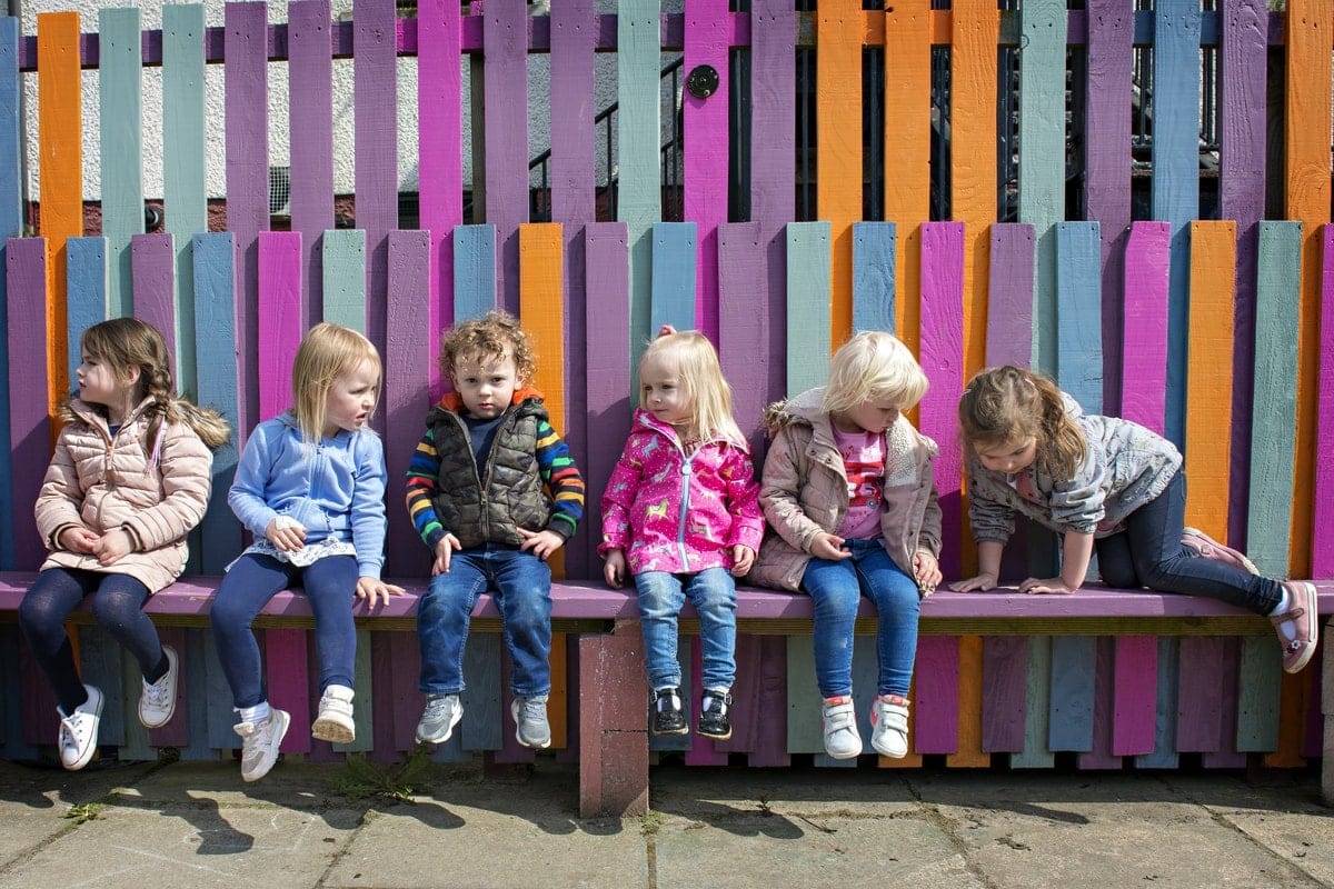 Open Aye. a group of children sit on a colourful bench.