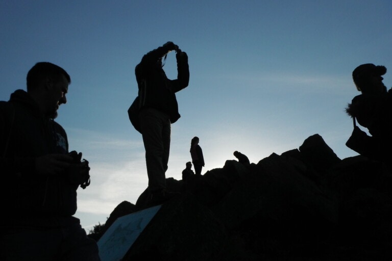 Open Aye. Silhouette of a group of people taking photographs at dusk.